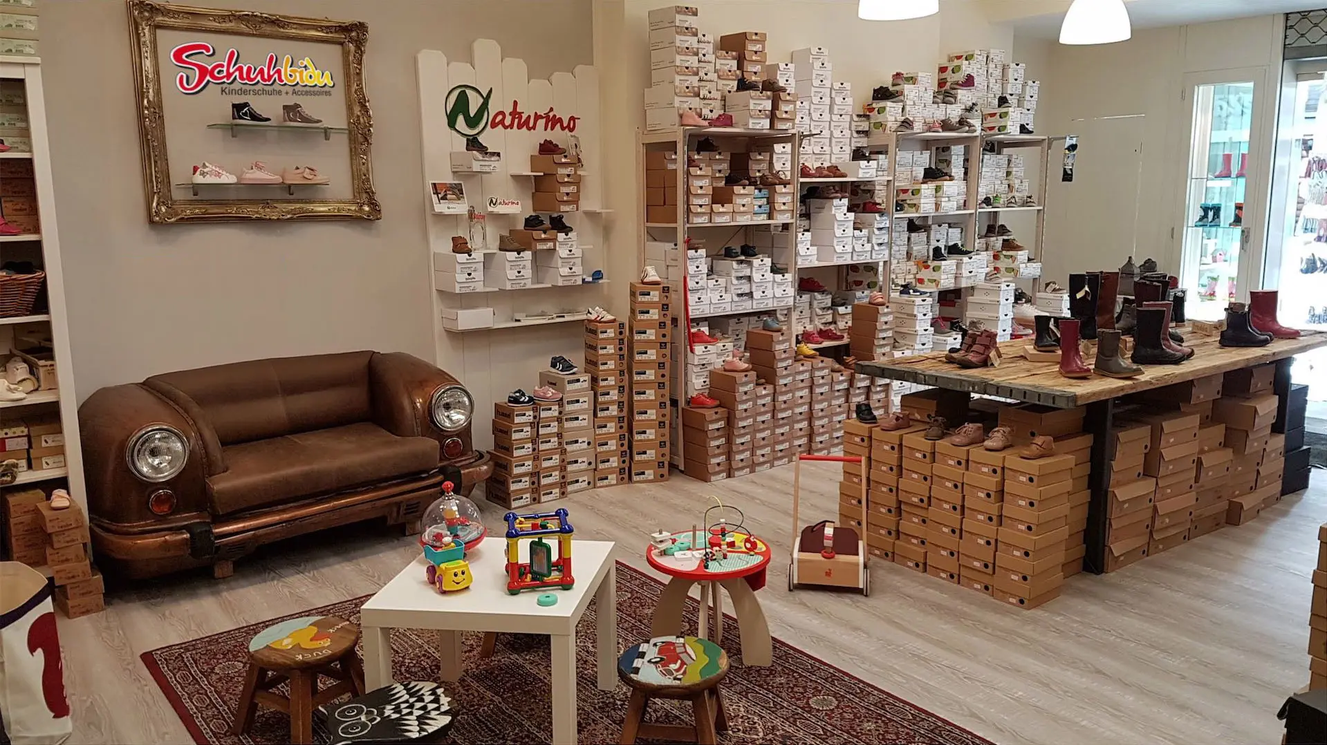 Verkaufsraum von Schuhbidu Kinderschuhe in Siegen mit Spielecke, Oldtimer-Sofa und Markenschuhen wie Naturino