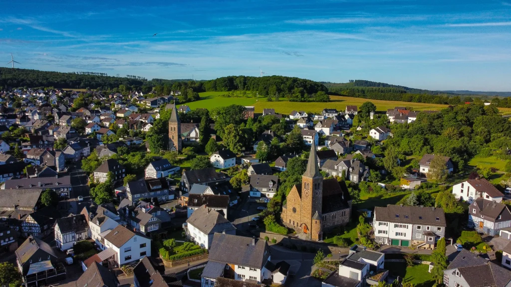 Sommerliche Luftaufnahme von Wilnsdorf im Siegerland mit den zwei Kirchtürmen, Fachwerkhäusern und grünen Hügeln